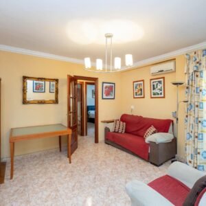 Imagen de un piso en venta con sofás granates y puertas de madera
