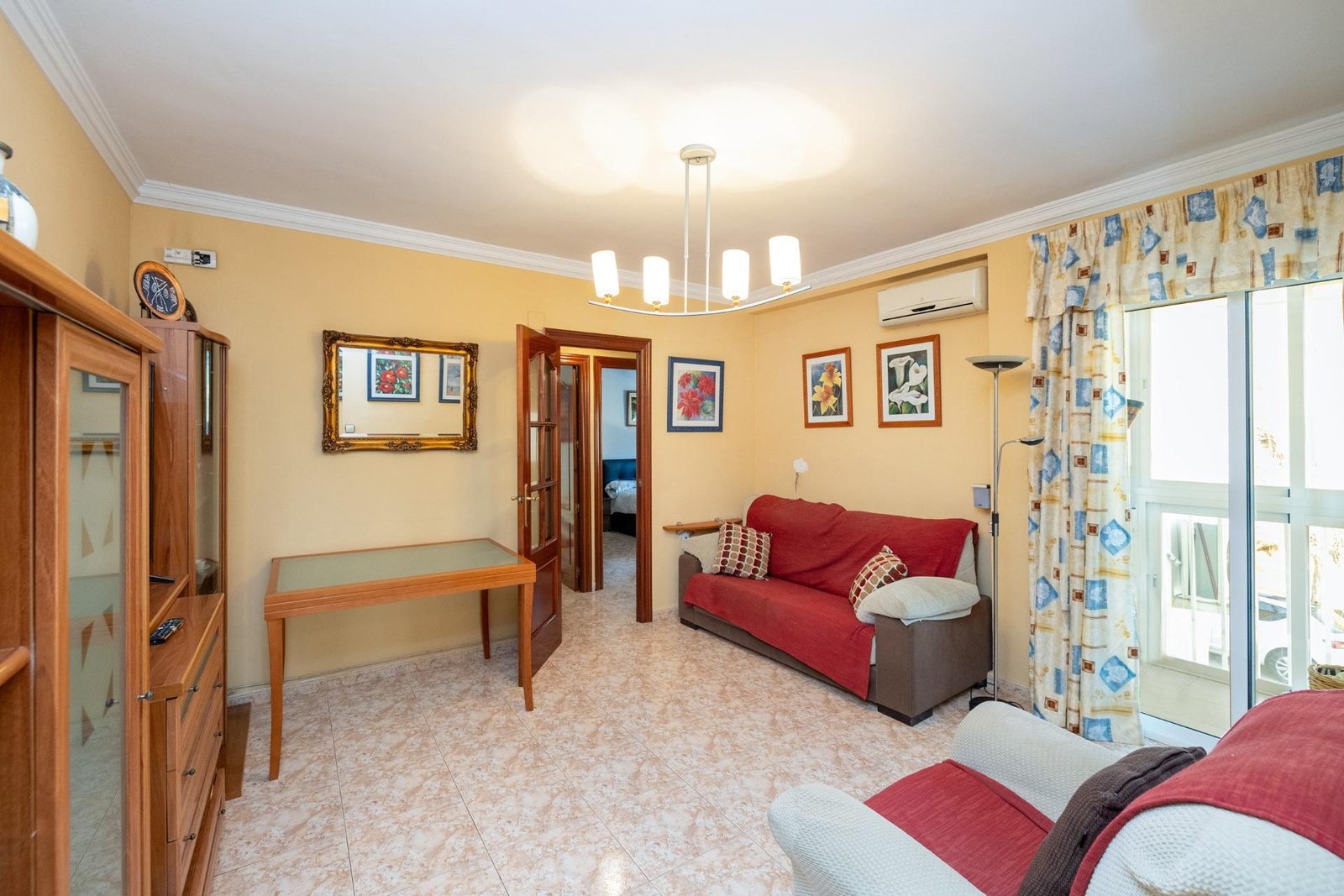 Imagen de un piso en venta con sofás granates y puertas de madera
